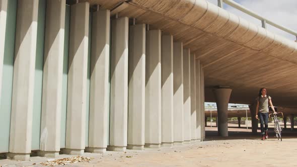 Mixed race man walking with a bike alt