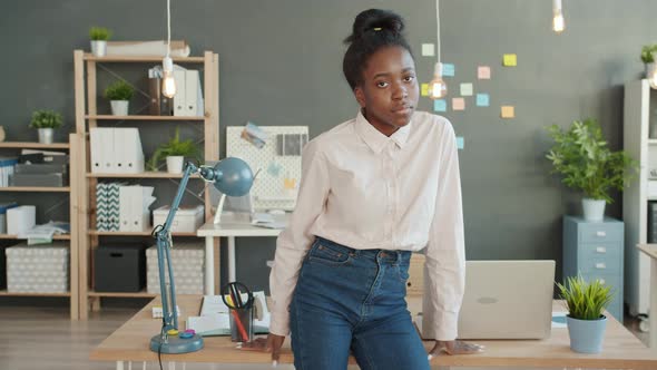 Portrait of Young Afro-American Woman Standing in Office and Looking at Camera with Serious Face alt