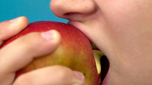 Teenager Girl with Braces on Her Teeth Eats a Red Apple on a Blue Background. Girl with Colored alt