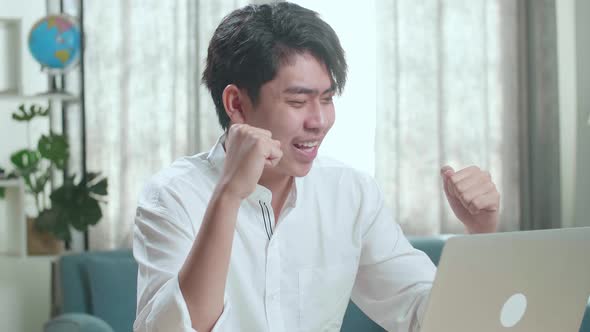 Close Up Of Asian Man Student Celebrating While Using Computer To Study Online At Home alt