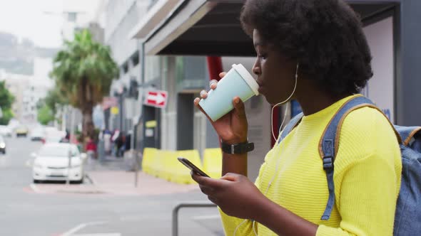 African american using her smartphone in street alt