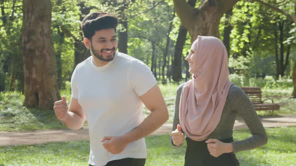 Arabian Couple in Activewear Jogging at Green Park During Morning Time alt