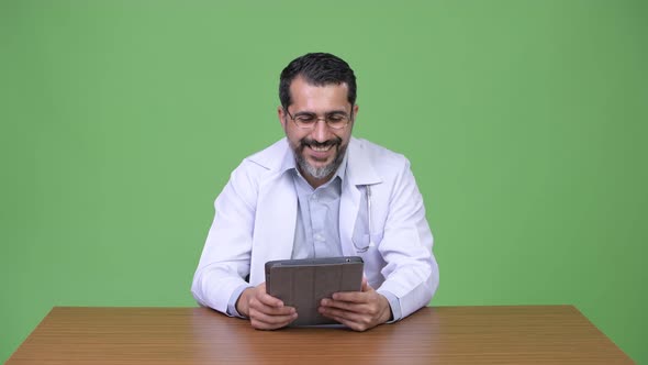 Happy Persian Bearded Man Doctor Thinking While Using Digital Tablet