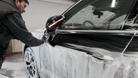 Male Worker in Black Glove with Foam Sponge Washing Car at Car Service Car Wash alt