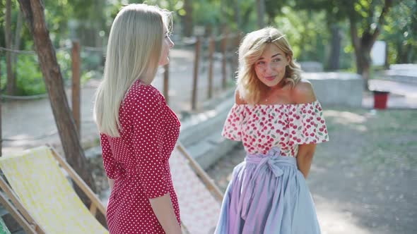 Two Young Attractive Women Talking and Walking in the Park alt