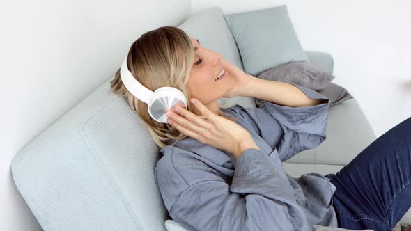 Portrait of cheerful european woman in headphones listening to music