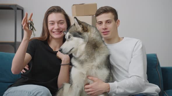 Happy Young Family Together with a Dog are Sitting on the Couch in a New Apartment alt