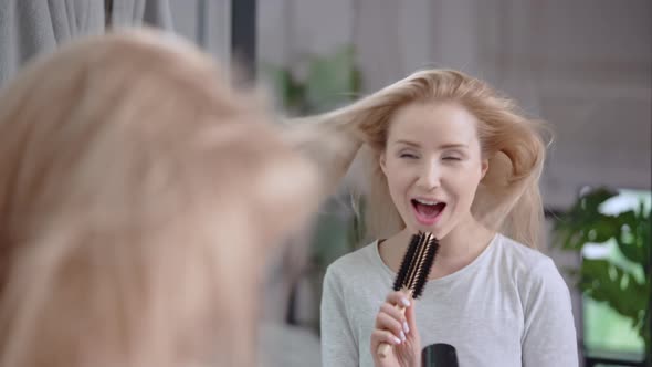 Female Dries with a Hairdryer Her Blond Long Hair