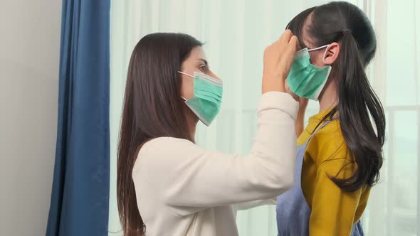 asian mom Putting on a Medical Mask on her daughter with care and tender alt