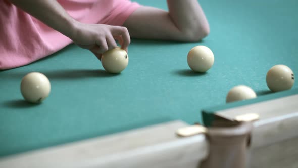 A Man Lying on a Billiard Table Plays with Billiard Balls Rolls Them Into a Pocket Closeup alt