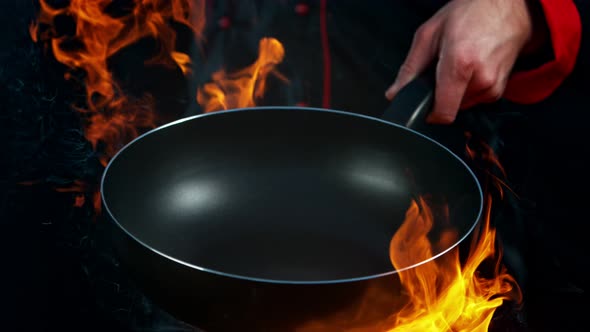 Super Slow Motion Shot of Chef Holding Empty Frying Pan and Flames at 1000Fps. alt