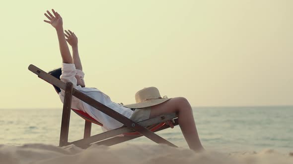 Young Asian women look at the sea view stretching with arms raised feeling to relax.