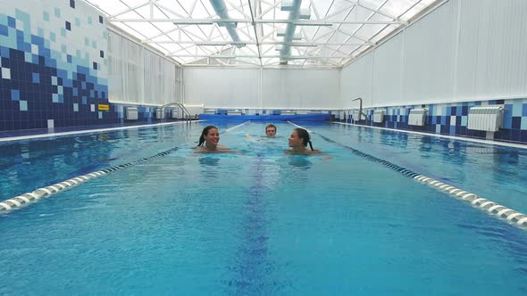 Three Happy Friends Swimming and Talking in the Pool alt