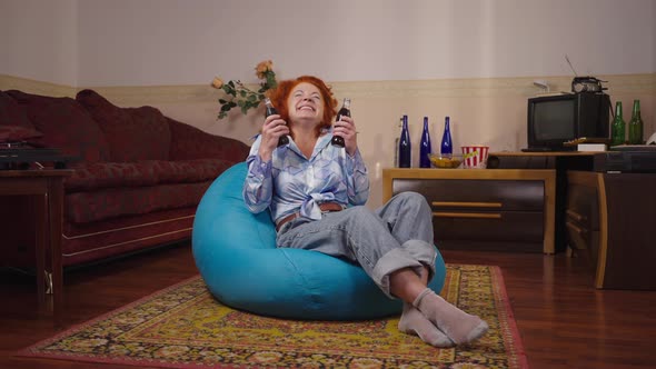 Wide Shot Carefree Joyful Retro Woman Sitting on Bag Chair with Soda Drink Bottles Smiling and alt