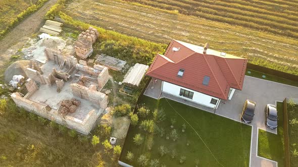 Top down aerial view of two private houses, one under construction with wooden roofing frame alt