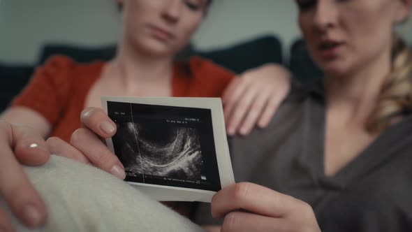 Hand holding ultrasound scan and two women in the background. Shot with RED helium camera in 8K. alt