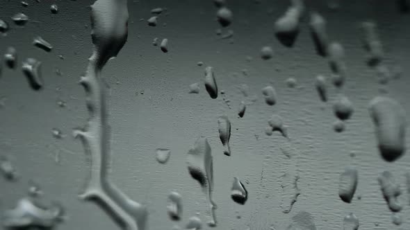 Close-up view of water drops falling on the glass.