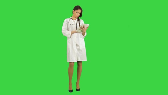 Pretty Female Doctor with Stethoscope Using Digital Tablet on a Green Screen, Chroma Key alt