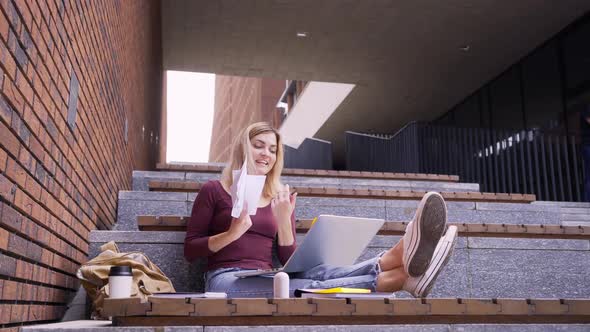 Female with Backpack Has Videocall Throwing Paper on Stone