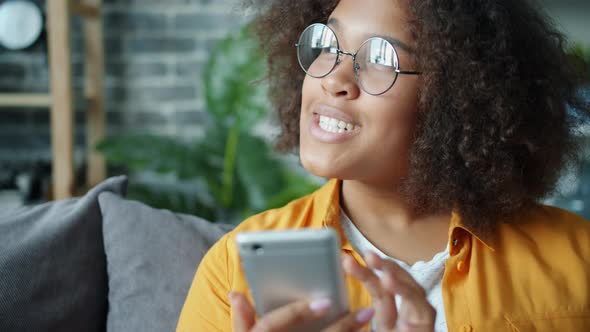 Happy African American Teenager Using Smartphone at Home Laughing alt