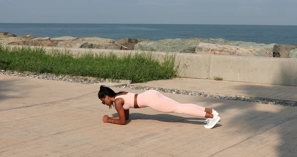 Fit sporty black African woman in top and leggings does leaning forward exercise outdoor.
