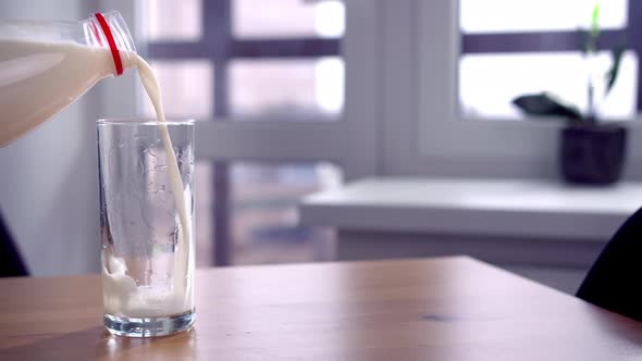 Closeup of a Woman Hand Pouring Milk From a Bottle Into a Glass Indoors Cinematic Shot