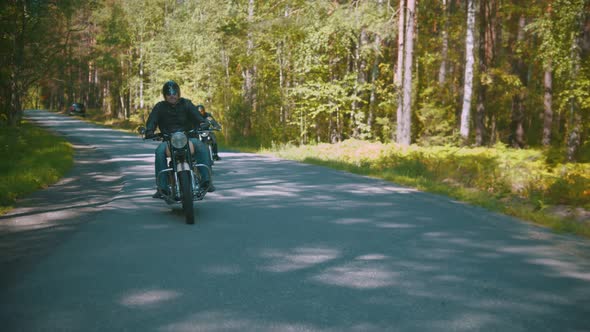 Two Brutal Motorcyclists in Helmets Riding Their Motorbikes in the Coniferous Forest alt