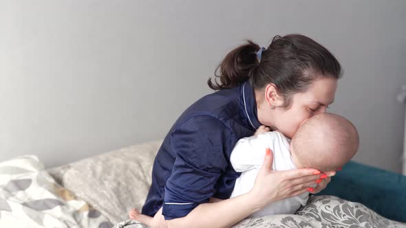 Mother Plays with Her Baby at Home on Her Lap