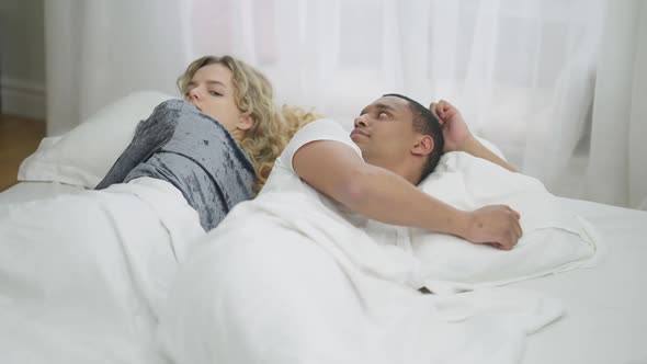 Argued Interracial Young Couple Lying in Bed Back to Back alt