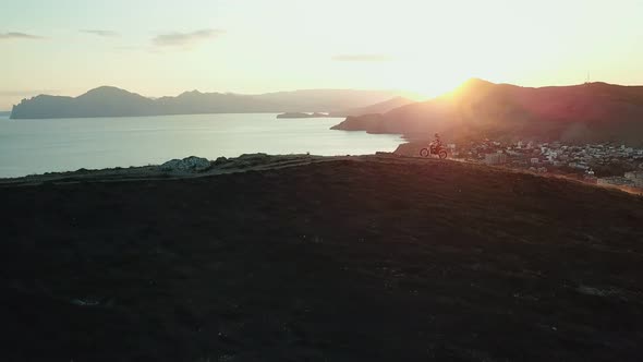 Drone View of Man on Motorbike Extremely Rides Across the Hills with Black Sea on Background 