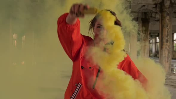 Dancing Woman Waving Yellow Smoke with Abandoned Building at Background alt