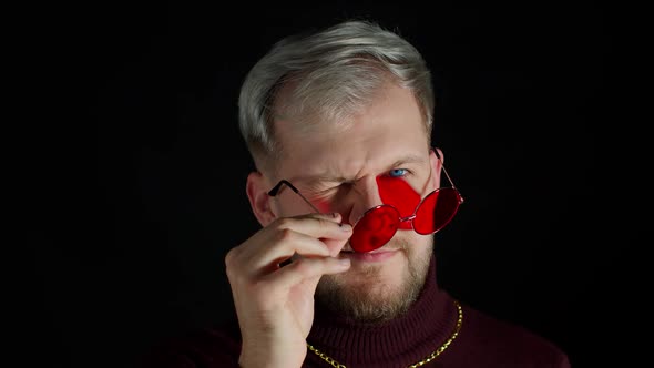 Seductive Young Man Wearing Sunglasses Charming Smile Wink Blink Eye Flirting on Black Background alt