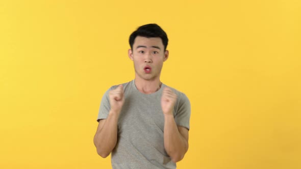 Half body of cute young Asian man making funny dance move isolated on yellow background