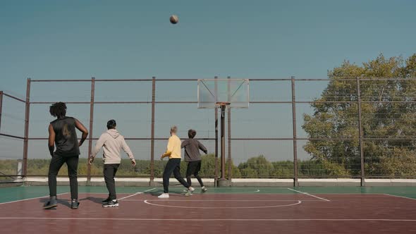 Man Scores Ball Into the Basket Team Cheers on a Basketball Court in Park alt