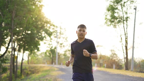 Sporty teenage boy running on natural park road with sunset time.