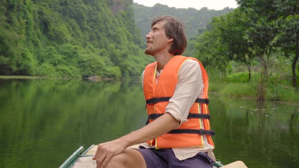 A Young Man on a Boat Having a River Trip Among Spectacular Limestone Rocks in Ninh Binh a Tourist alt