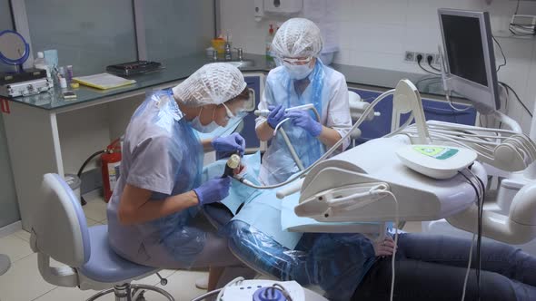 Woman Dentist Treating Teeth to Woman Patient in Clinic. Female Professional Doctor  alt