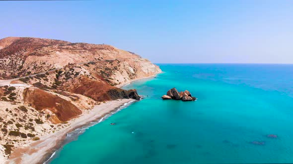 Aerial view of Aphrodite's Rock as camera pulls away along the beach and coastline with beautiful vi alt