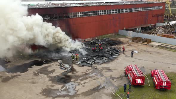 Aerial View of Firemen Fighting with Fire Near Old Factory Biulding in Industrial Area alt