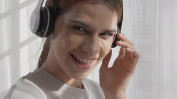 Happy young asian woman wearing headphones listening music while dancing and singing with fun. alt