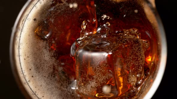 Super Slow Motion Detail Shot of Ice Cube Falling Into Glass of Fresh Cola Drink at 1000Fps alt