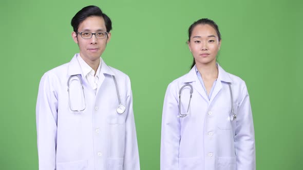 Young Asian Couple Doctors Giving Thumbs Up Together