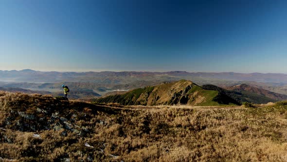 Aerial Slider Shot Man Walking on Mountain Ridge at Sunrise alt