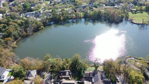An aerial drone view of Grant Pond in a Long Island, NY suburb. The camera truck right, tilted down alt