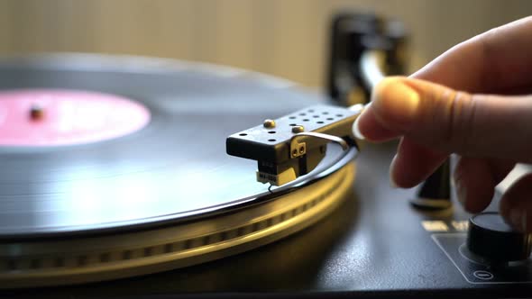 Female Hand Putting Stylus on the Vinyl Record on DJ Turntable Record Player Close Up. The Rotating