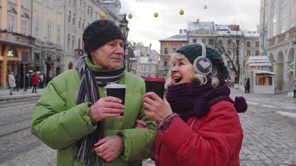 Senior Old Couple Tourists Grandmother Grandfather Traveling Drinking Hot Drink Tea in City Center alt