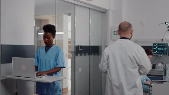 Practitioner Nurse in Medical Uniform Typing Recovering Treatment on Laptop alt