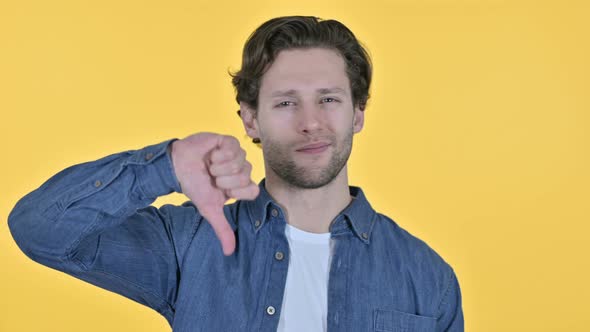 Thumbs Down By Disappointed Young Man on Yellow Background alt