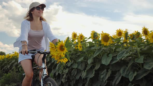 Woman Riding a Bicycle Along a Sunflower Field