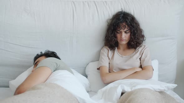 Angry Caucasian Woman Looking at Sleeping Husband Arab Guy Lying in Bed Together alt